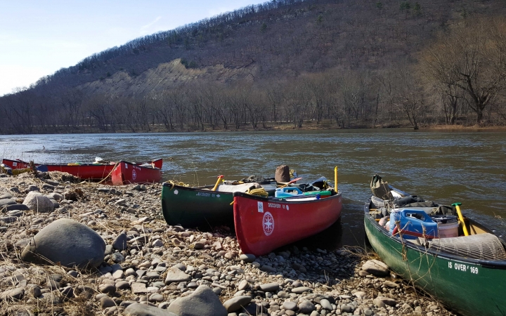 a group of canoes rest on a rocky shore